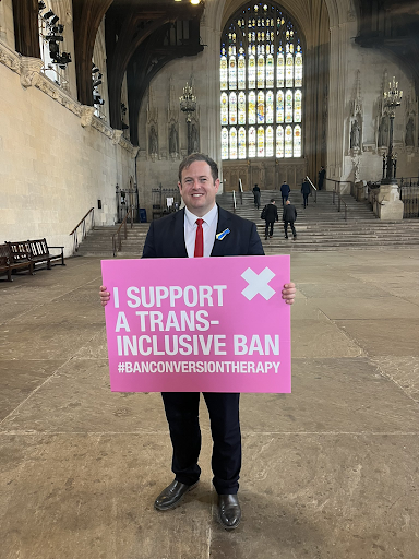 MP holding placard "I support a trans-inclusive ban"