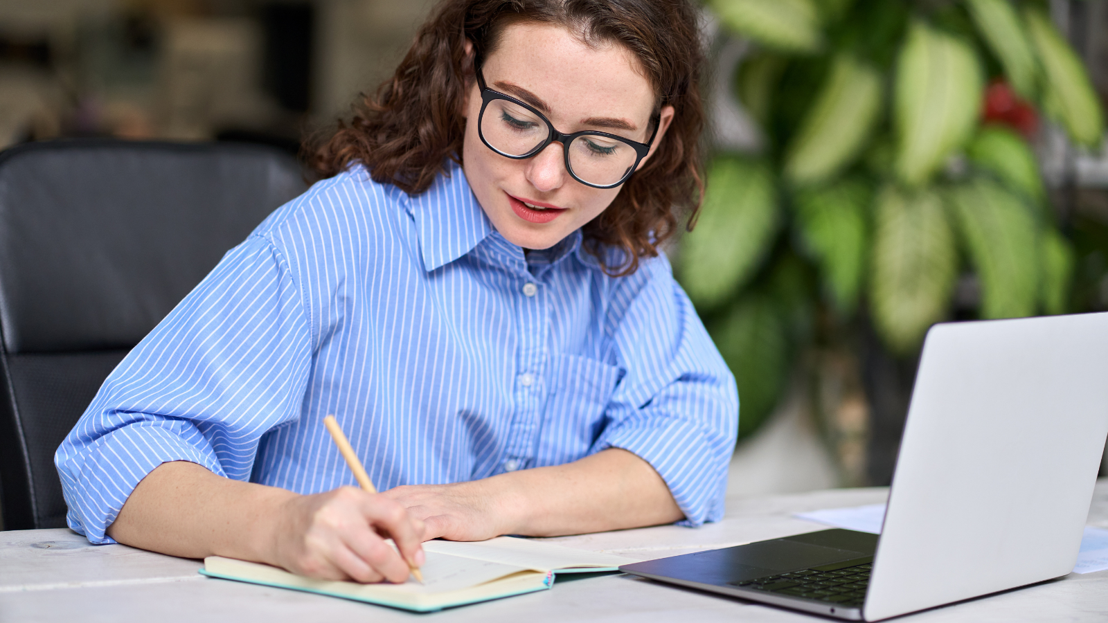 Woman with laptop writing notes
